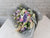 Bouquet of flowers wrapped in gray paper on a white surface with a light gray brick wall background