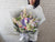 Person holding a bouquet of flowers against a white brick wall