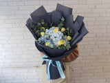 Bouquet of flowers wrapped in black paper with a blue ribbon 